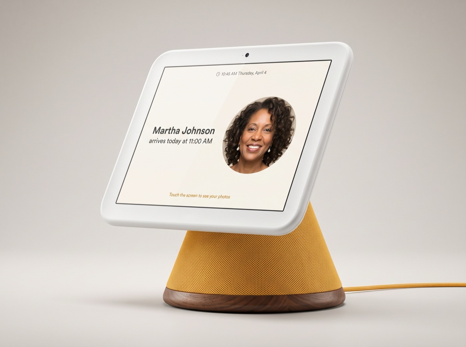 Honor Frame hardware prototype: white-framed touchscreen on a marigold fabric stand with walnut base, showing a caregiver arrival — Martha Johnson arrives today at 11:00 AM